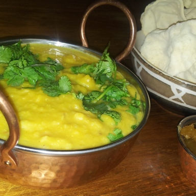 Picture of pumpkin and lentil soup in a bowl, next to pappadums and mango chutney